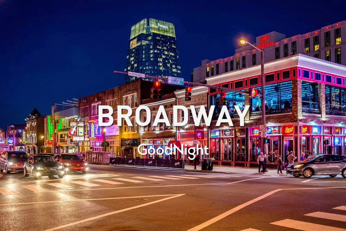 This image captures a vibrant Nashville street at night, featuring colorful neon signs, a bustling sidewalk filled with people, and traffic lights illuminating the scene. The atmosphere is charged with energy and excitement, perfectly evoking the city’s famed nightlife.