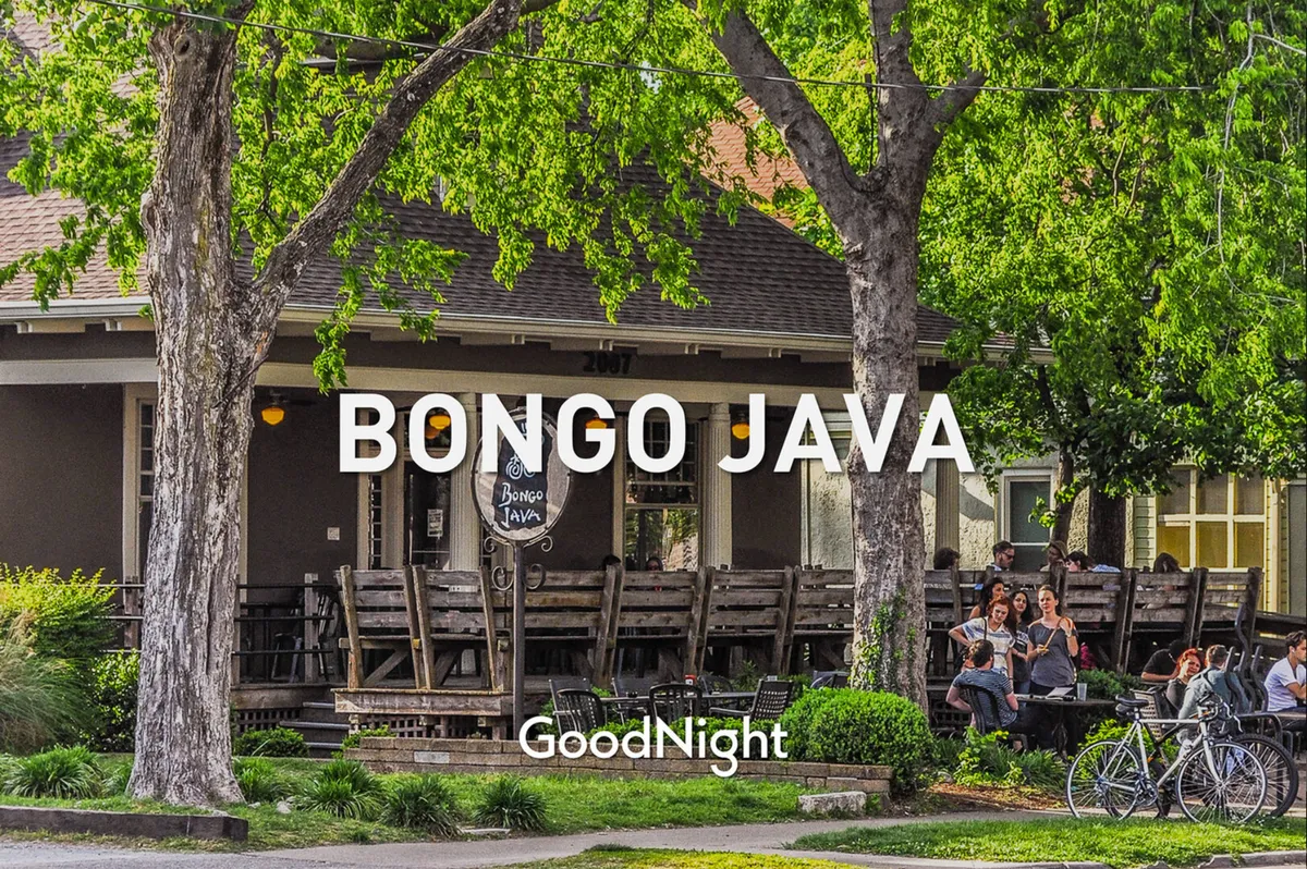 This image features an inviting exterior setting at Bongo Java, a popular local coffee shop. The outdoor seating area is bustling with people socializing, and there are bicycles parked nearby, highlighting a lively, pet-friendly community environment. The scene conveys a sense of neighborhood vibrancy and walkability.