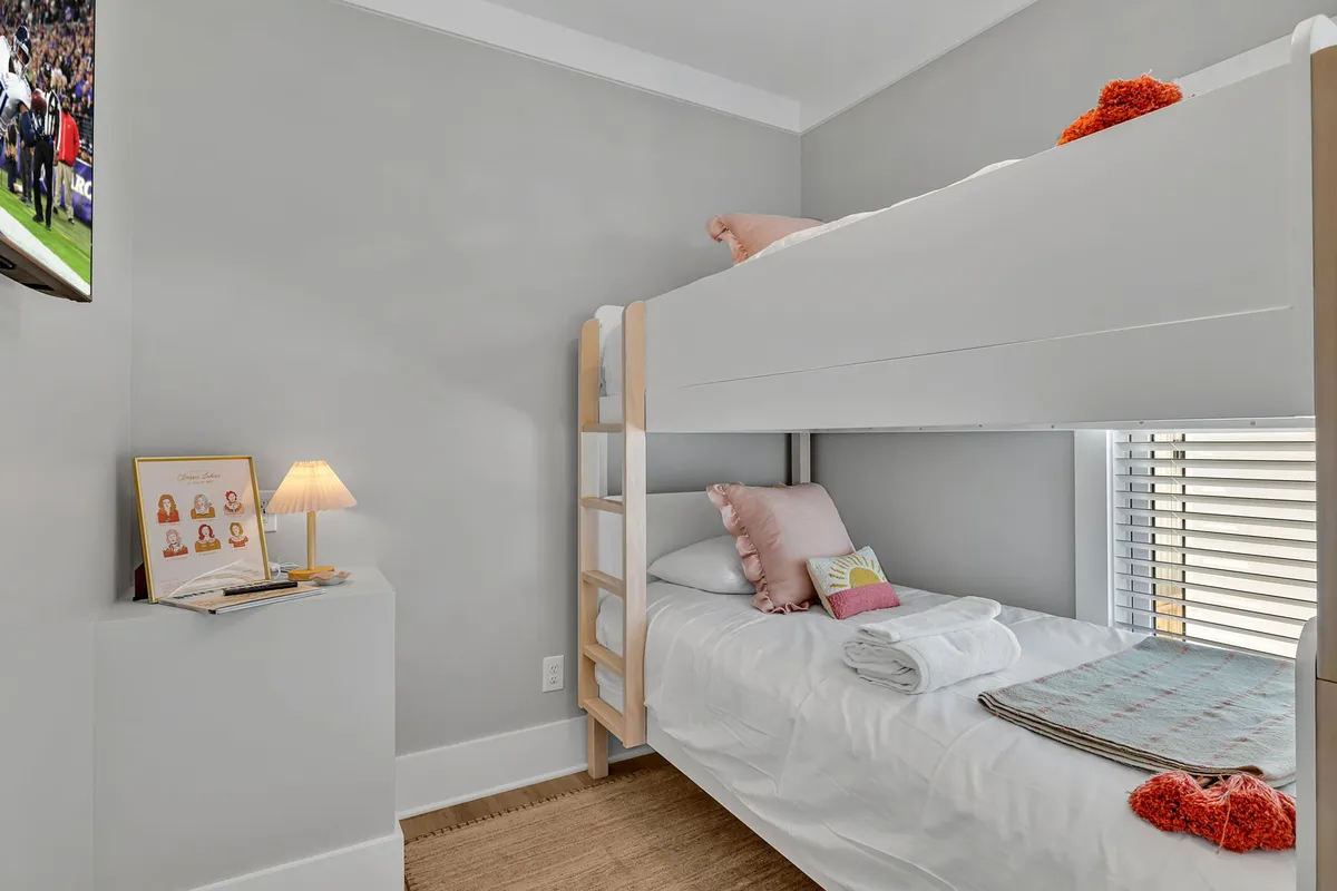 A playful and relaxed bunk room with a bunk bed, decorative pillows, table lamp, and a TV. The setup is ideal for children or extra guests, offering both fun and privacy.