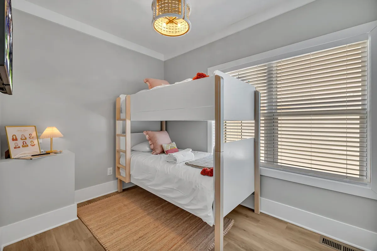 A playful and inviting kids' bedroom featuring a bunk bed with decorative pillows, a table lamp, and a woven rug. The space feels welcoming for families, with thoughtful details that cater to children and create a sense of home away from home.